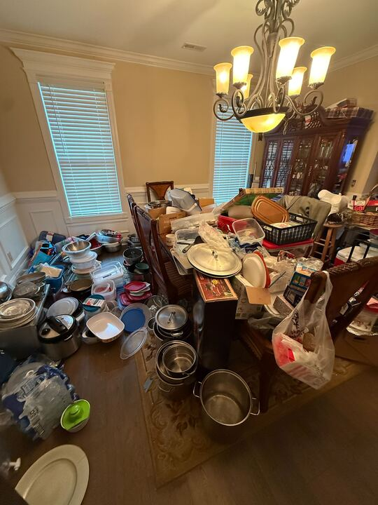 Dining room overflowing with cookware and dishes, cluttering table and floor.