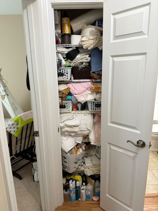 A cluttered, open closet filled with various items, including linens and toiletries.