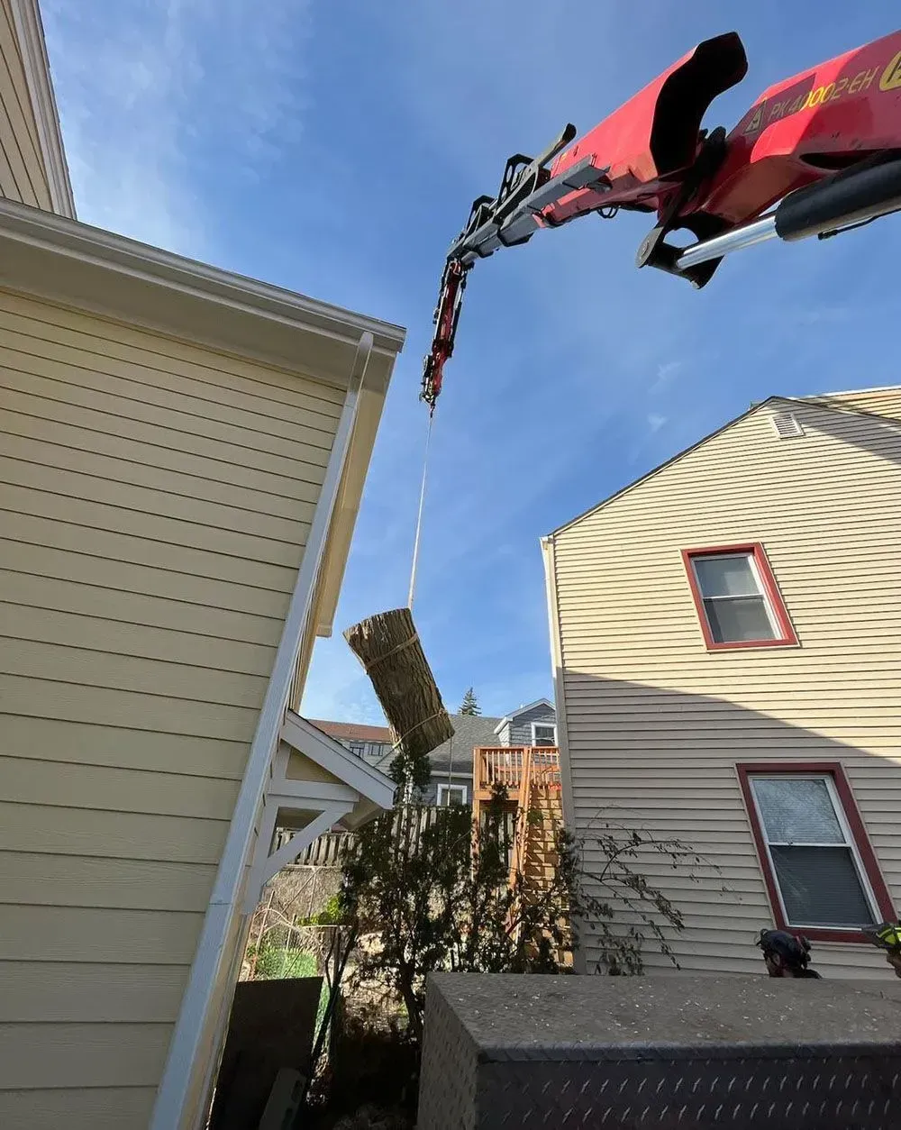 A crane is lifting a piece of wood between two houses