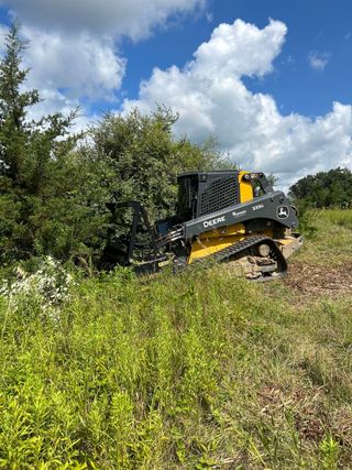 A bulldozer is driving through a grassy field.