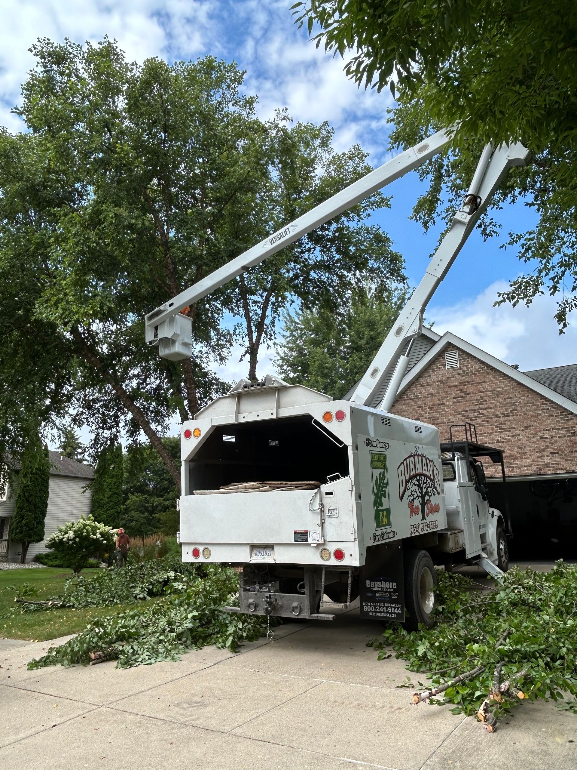 A tree chipper is cutting a tree in front of a house.