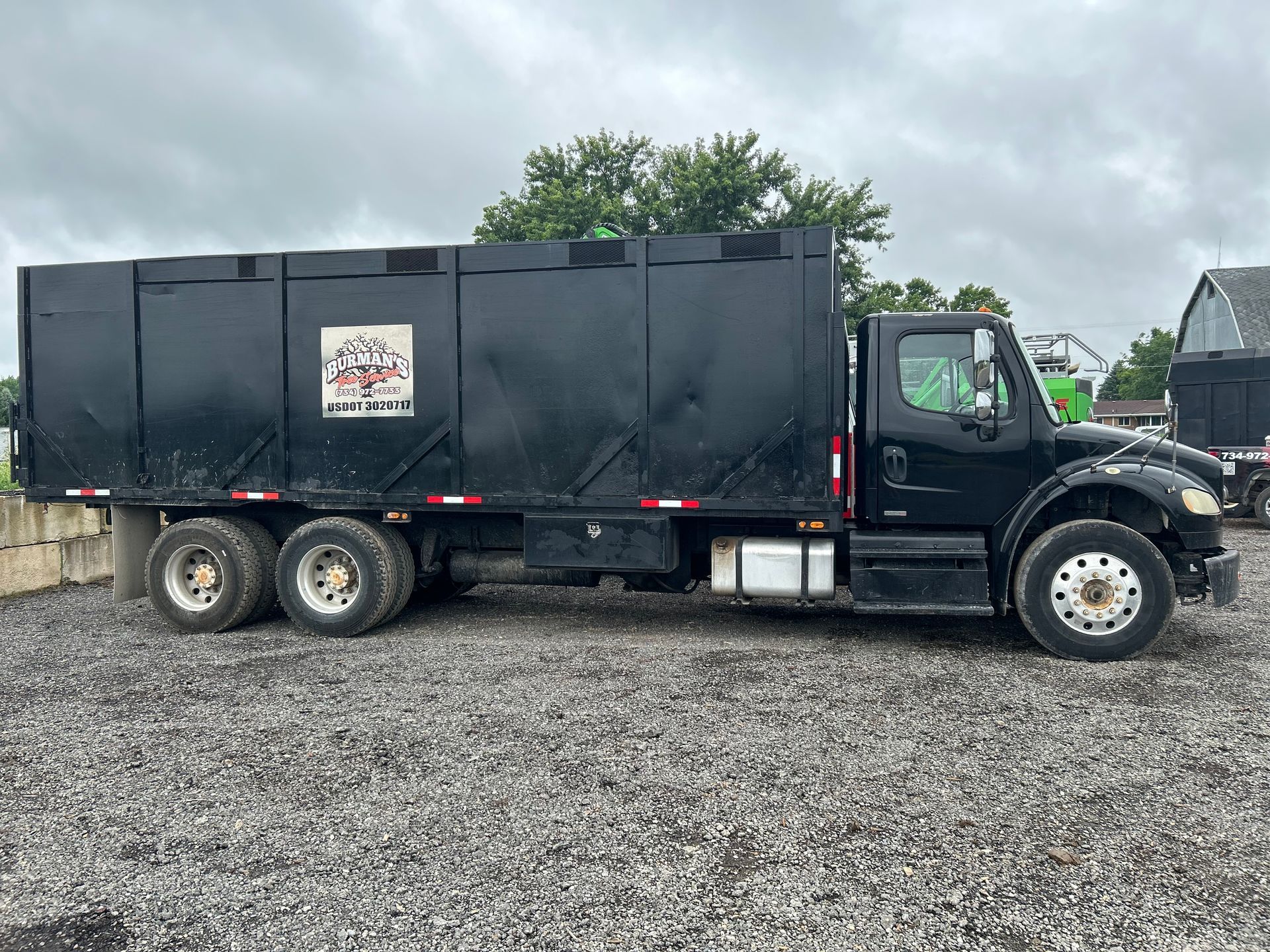 A black dump truck is parked in a gravel lot.