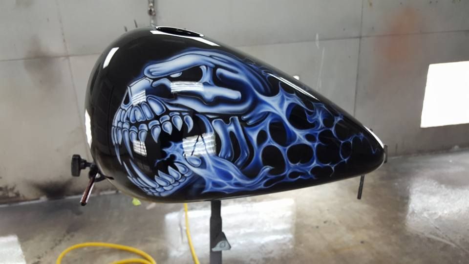 A motorcycle tank with a skull painted on it