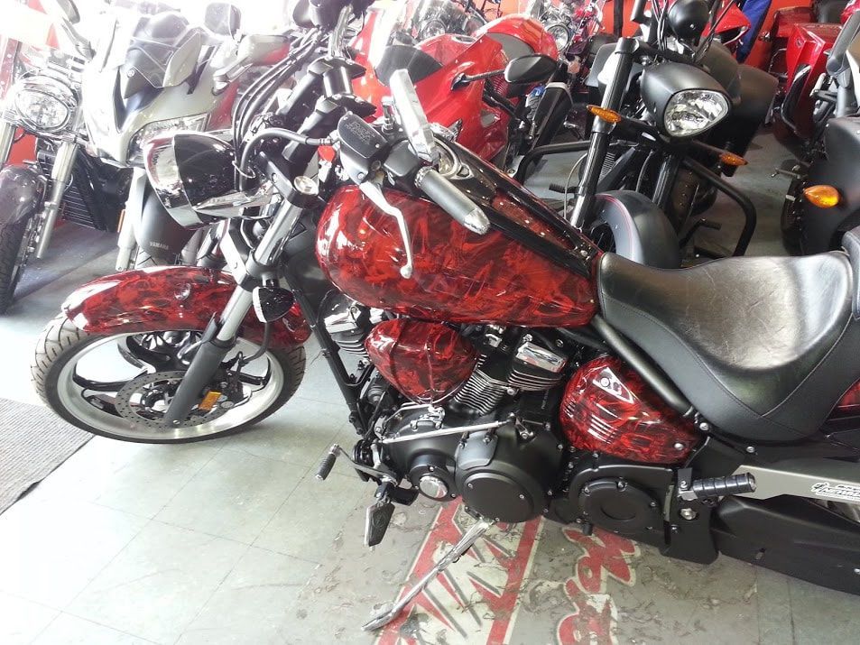 A red motorcycle is parked in a showroom next to other motorcycles.