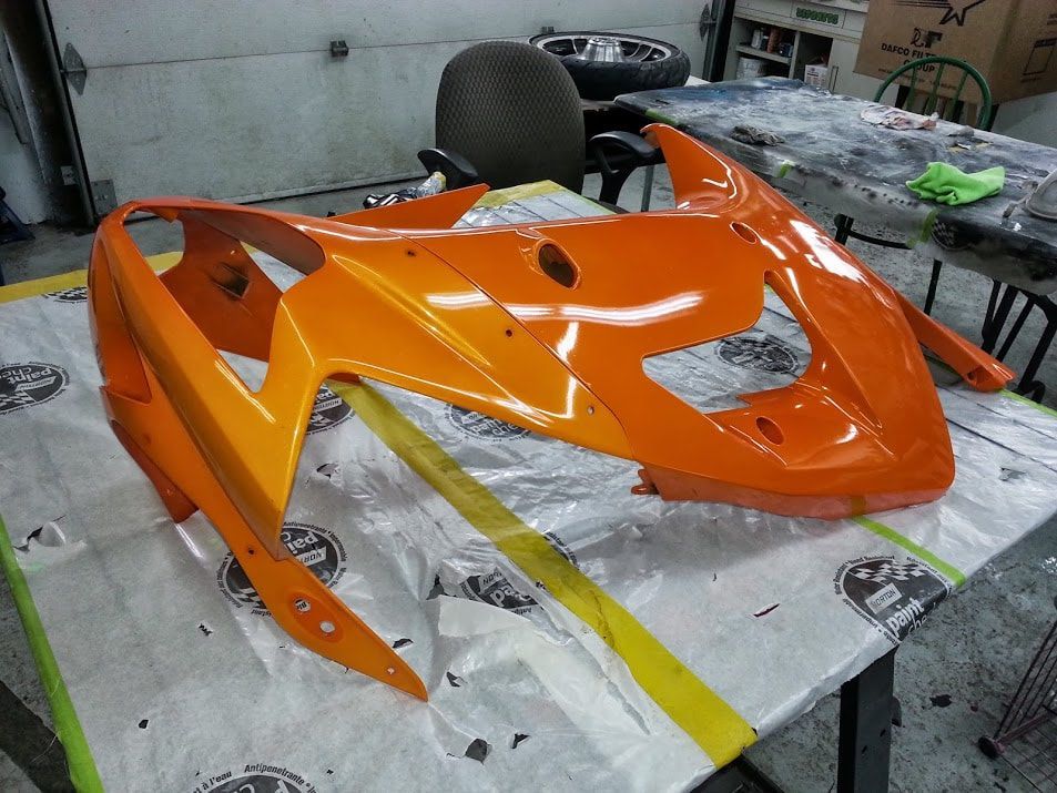 An orange motorcycle is sitting on a table in a garage