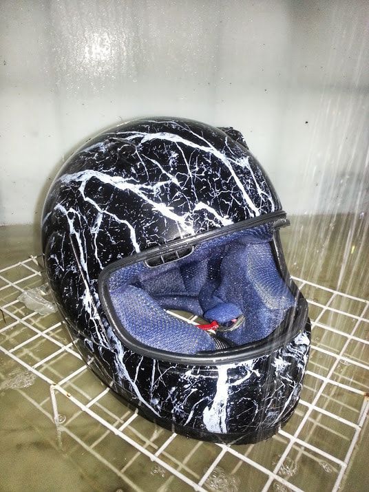 A black and white motorcycle helmet is sitting on a wire rack.