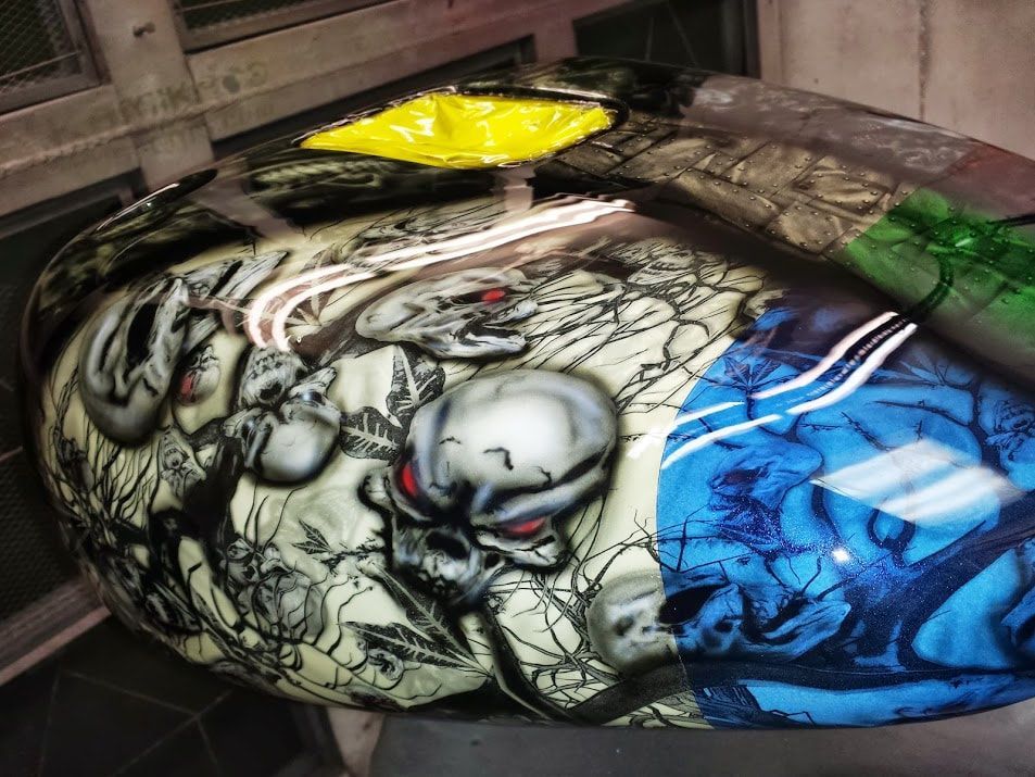 A motorcycle tank with a skull painted on it.