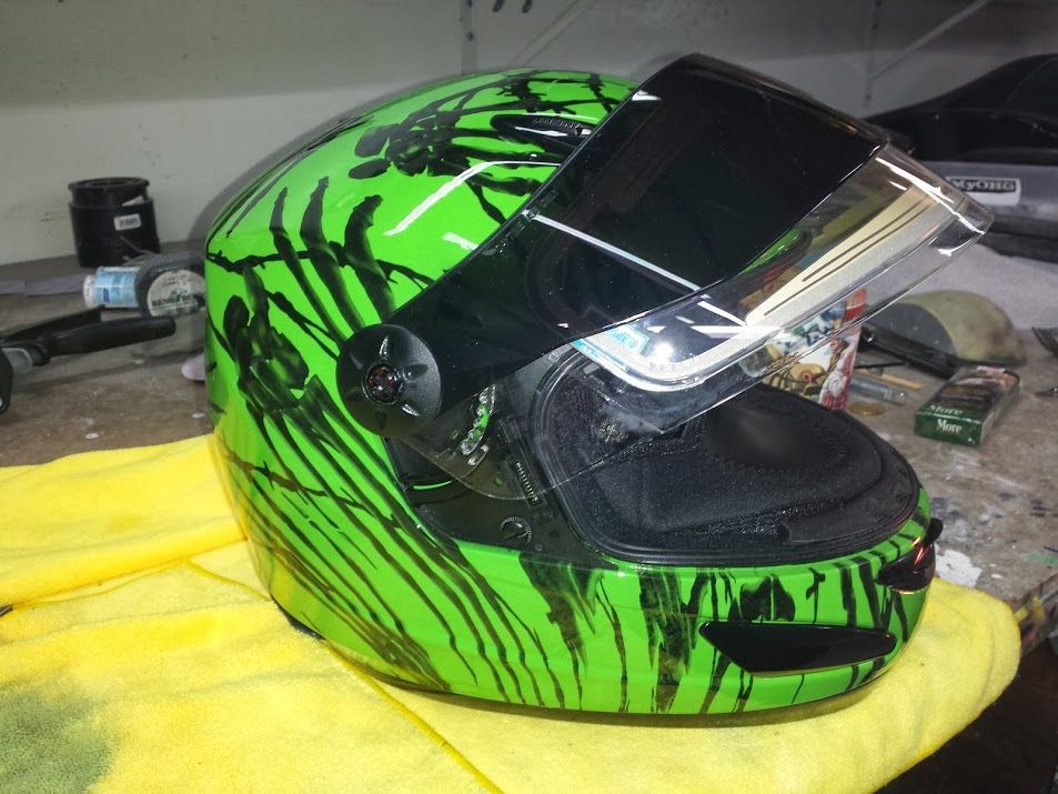 A green motorcycle helmet is sitting on a yellow towel