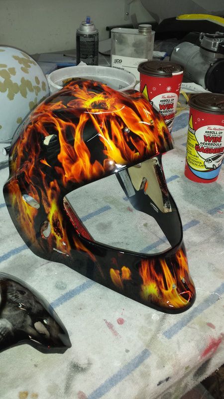 A helmet with flames painted on it is sitting on a table.