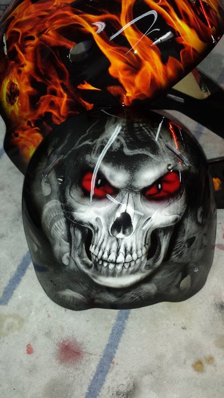 A skull with red eyes is painted on a motorcycle helmet.