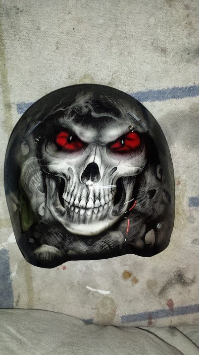 A skull with red eyes is painted on a motorcycle helmet.