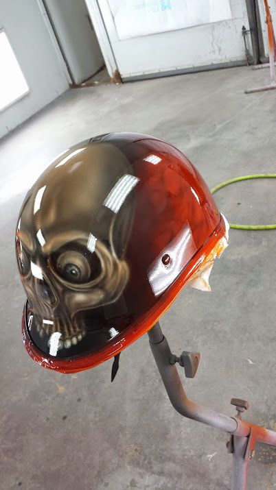 A helmet with a skull painted on it is sitting on a stand.