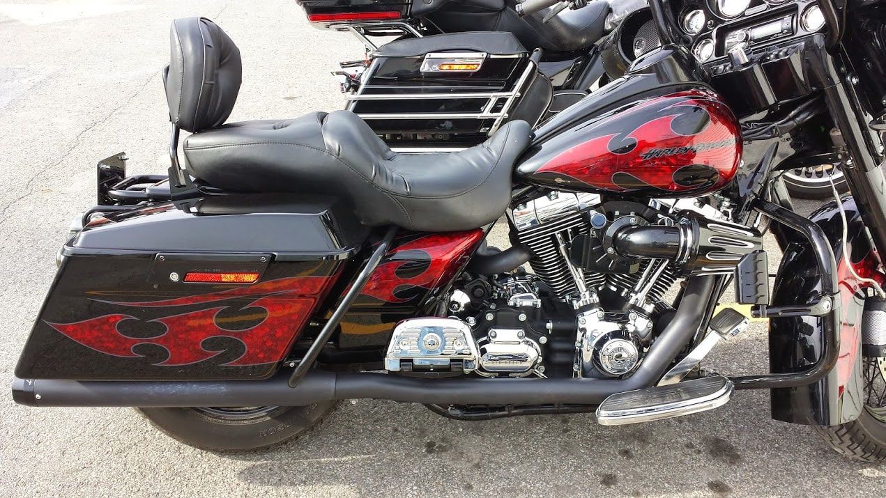 A black and red harley davidson motorcycle is parked on the side of the road.