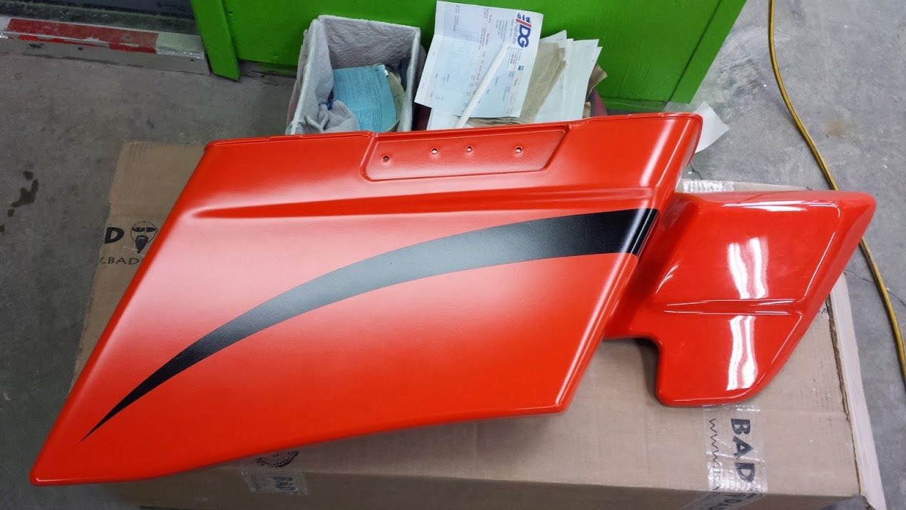 An orange and black motorcycle fender is sitting on top of a cardboard box.
