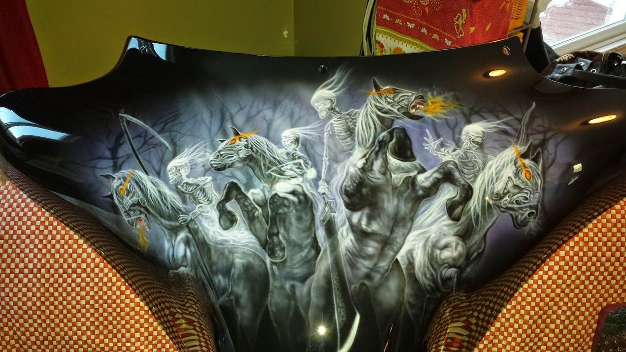 A painting of a group of horses is on the back of a car hood.