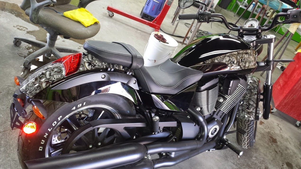 A black motorcycle is parked in a garage next to a chair.