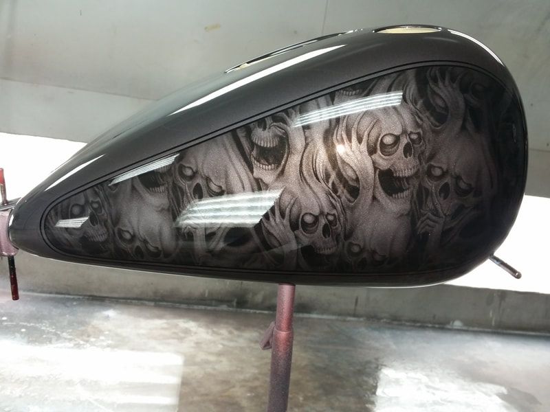A motorcycle tank with skulls and flames painted on it