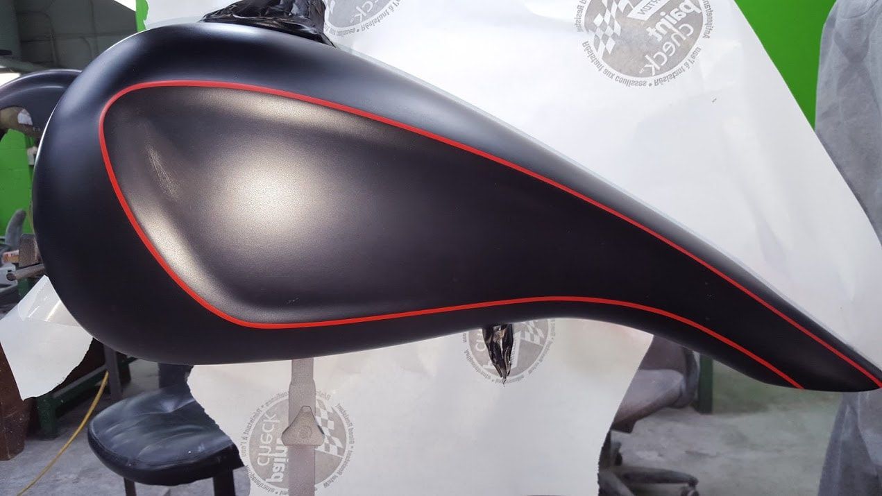 A black motorcycle tank with a red stripe on the side