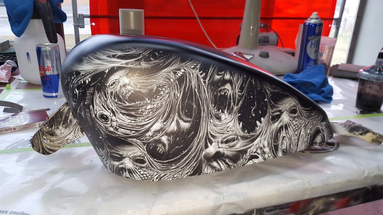 A motorcycle tank with a skull design on it is sitting on a table.