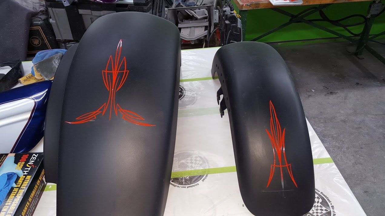 Two black motorcycle fenders with red stripes on them are sitting on a table.