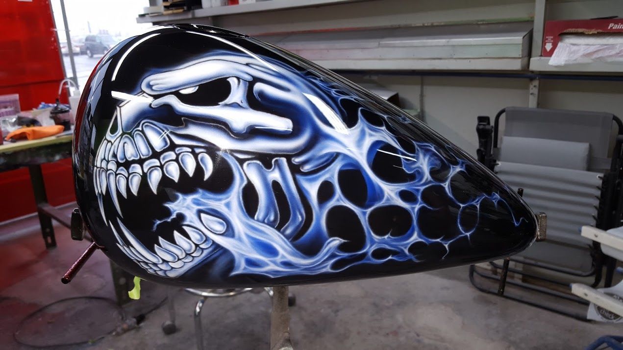 A motorcycle tank with a skull painted on it