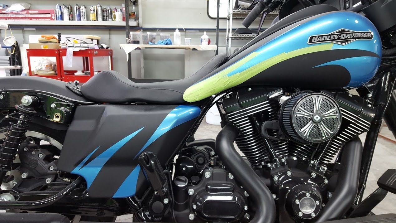 A blue and black harley davidson motorcycle is parked in a garage.