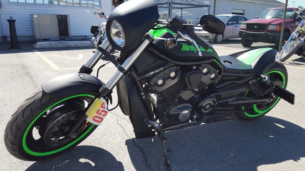 A black and green motorcycle is parked in a parking lot.