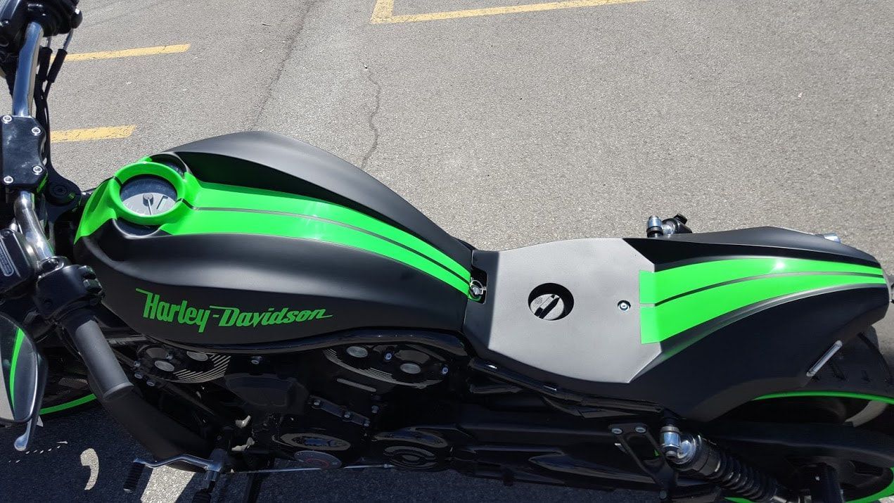 A black and green harley davidson motorcycle is parked on the side of the road.