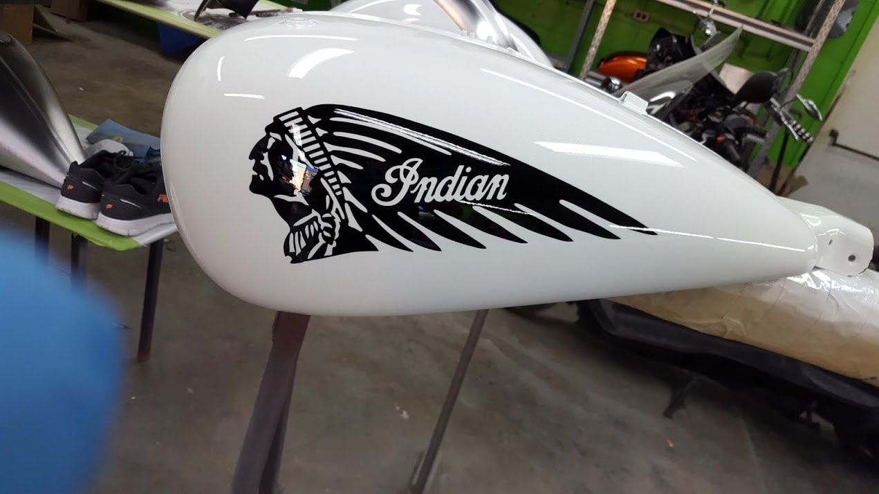 A white motorcycle tank with the word indian on it