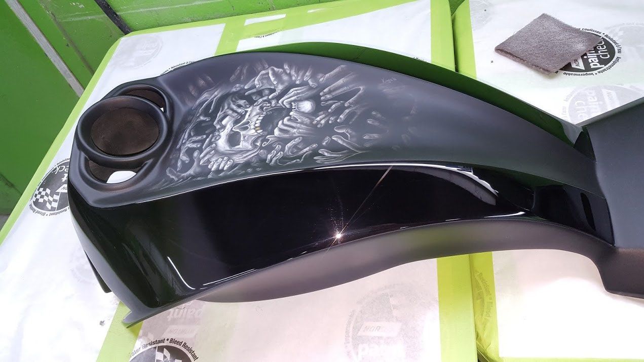 A black motorcycle tank is sitting on top of a green table.