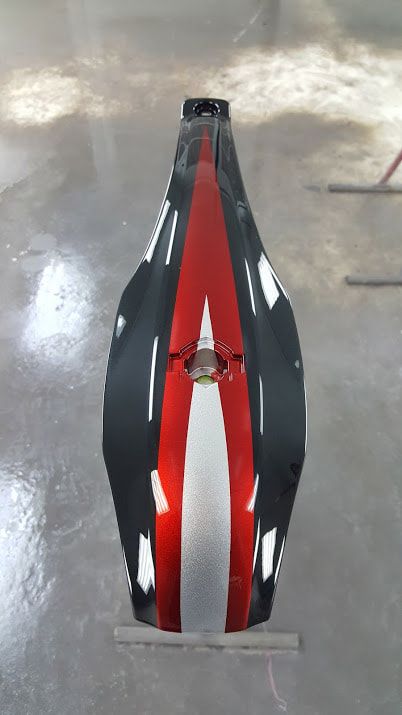 A red and black motorcycle is sitting on a concrete floor.