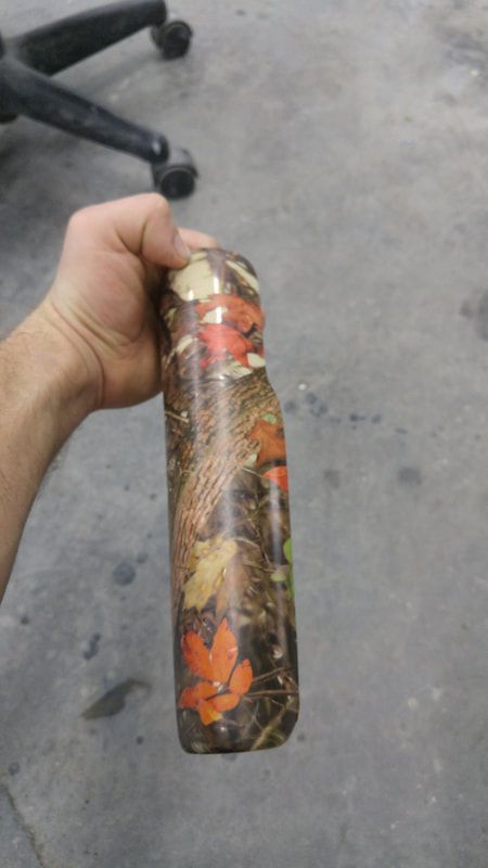 A person is holding a camouflage bottle in their hand.