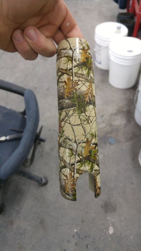A person is holding a piece of wood with a camouflage pattern on it.