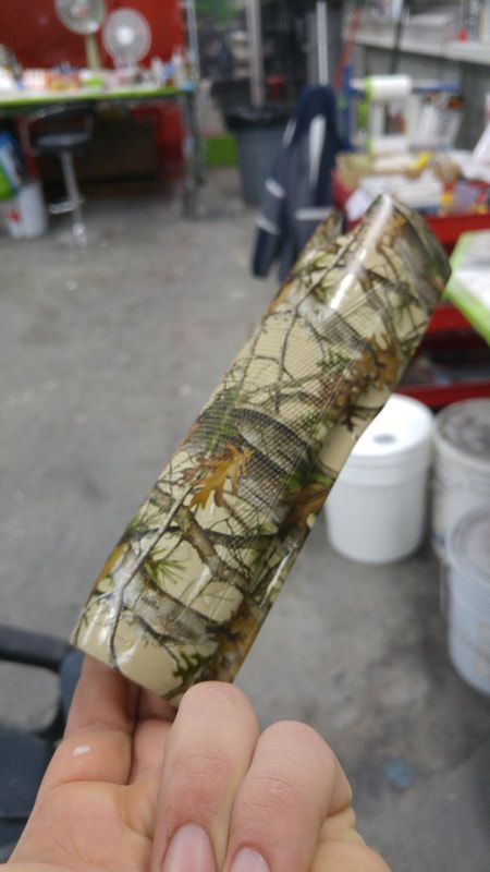 A person is holding a piece of camouflage tape in their hand.