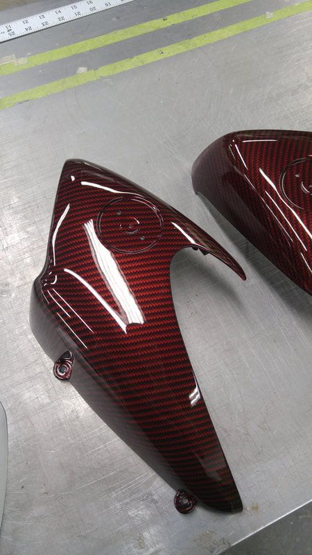 A pair of red motorcycle fender covers are sitting on a table.