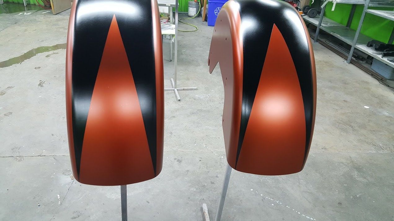 A pair of motorcycle fenders painted orange and black