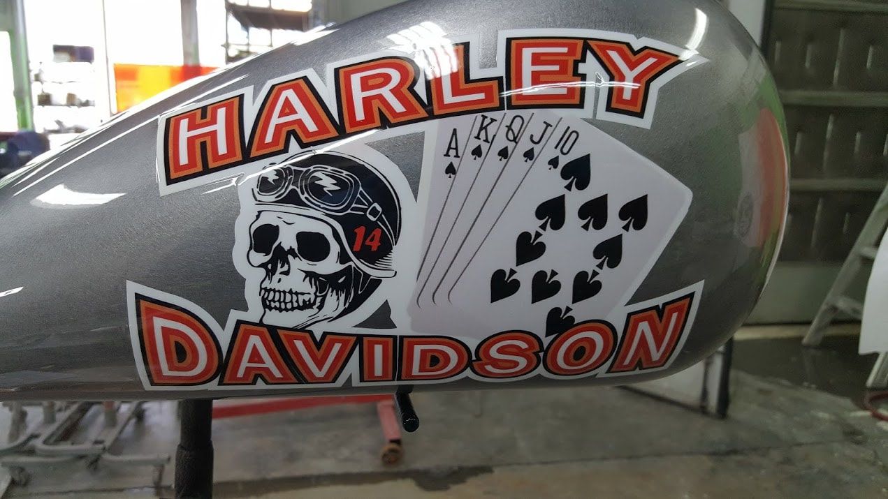 A harley davidson motorcycle tank with a skull and playing cards on it