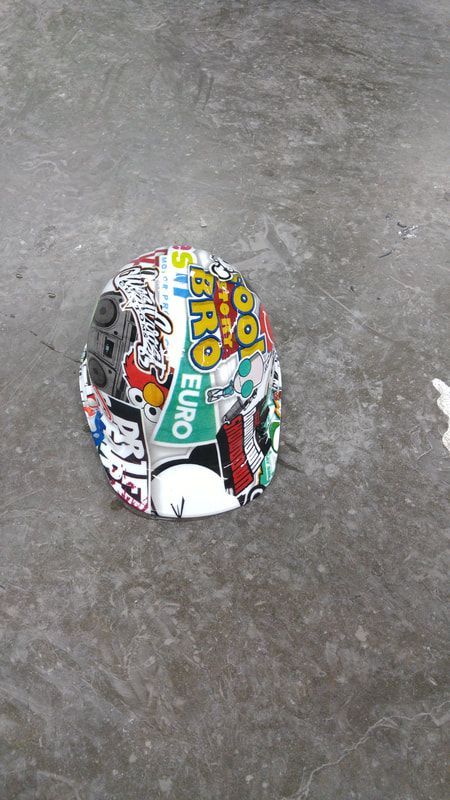 A helmet with stickers on it is laying on the ground.