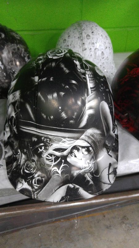 A black and white helmet with a woman on it is sitting on a table.