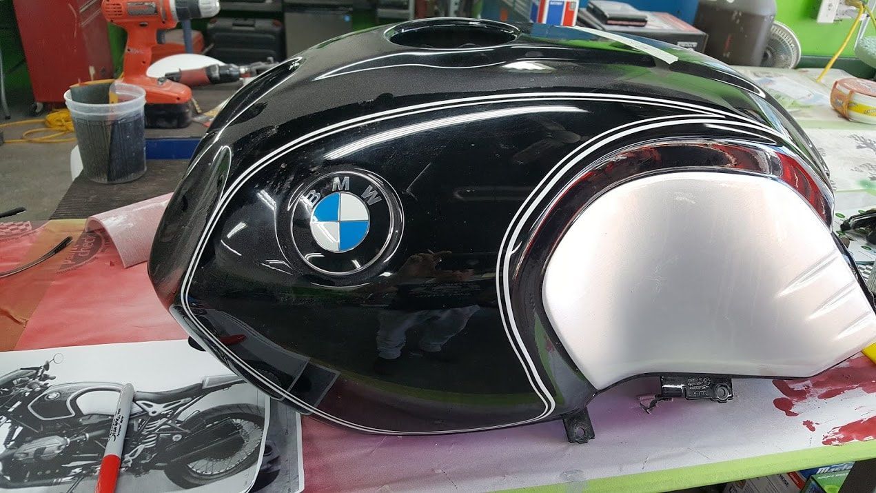 A black bmw motorcycle fuel tank is sitting on a table.