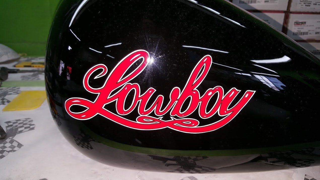 A black motorcycle tank with red lettering that says lowboy