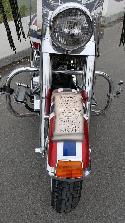 A red white and blue motorcycle is parked on the side of the road.