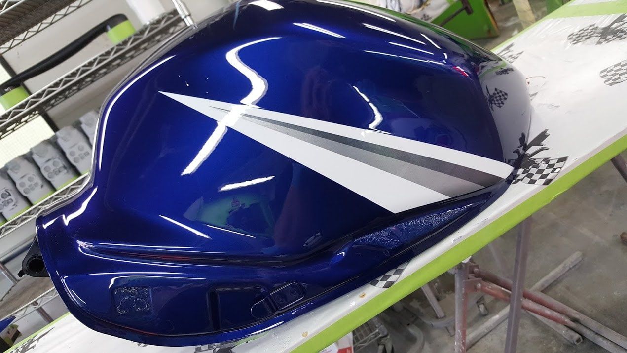 A blue and white motorcycle tank is sitting on a table.