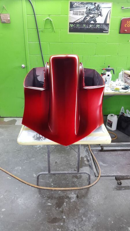 A red object is sitting on a table in front of a green wall.