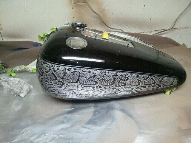 A black motorcycle tank with a snake print on it