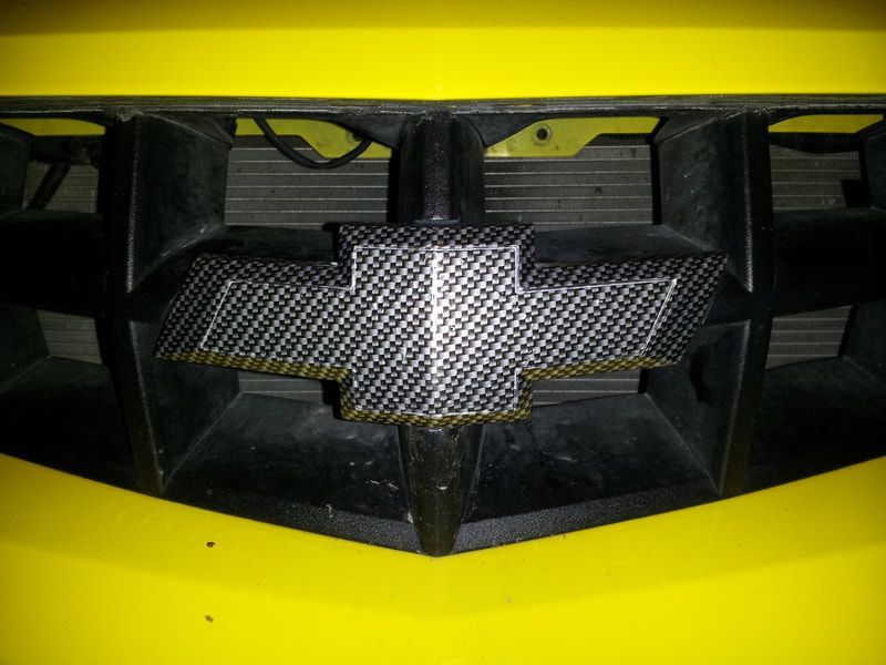A close up of a yellow chevrolet grille
