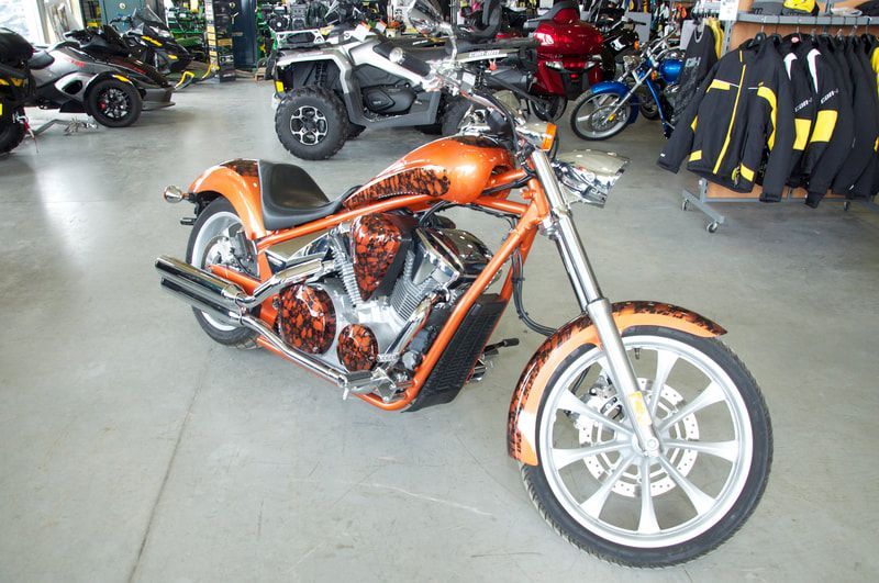 An orange motorcycle is parked in a showroom.