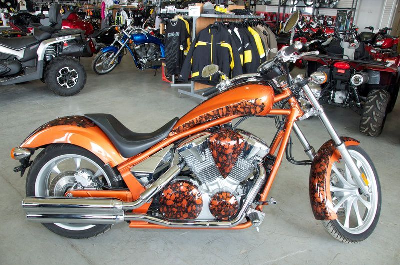 An orange motorcycle is parked in a garage