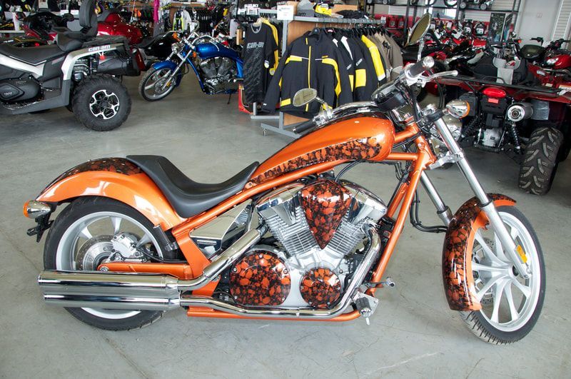 An orange motorcycle is parked in a showroom