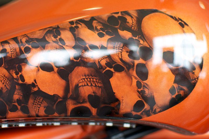 A close up of a motorcycle tank with skulls painted on it